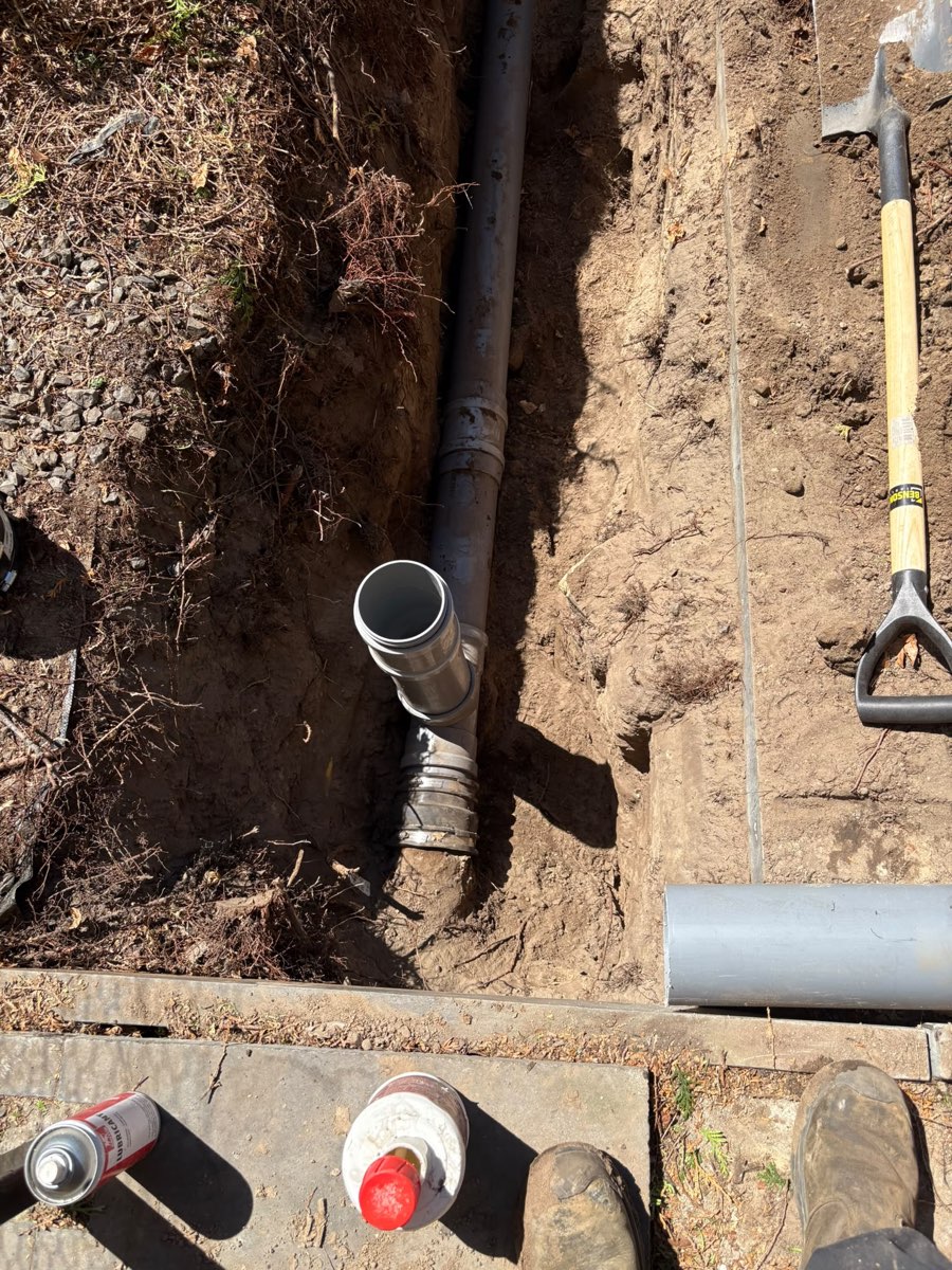 Sleuf met nieuwe rioolbuis in de tuin